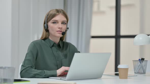 Woman with Headset Smiling While Working on Laptop