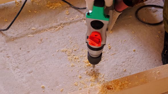 Drilling holes in the concrete floor of the house with a puncher drill for the installation of woode