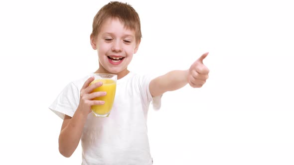 Elementaryschool Aged Caucasian Boy Gladly Drinking Orange Juice From Glass and Showing Ok at Camera