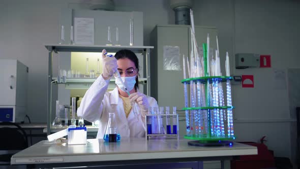 Female Microbiologist Looking Into Microscope in Medical Science Laboratory