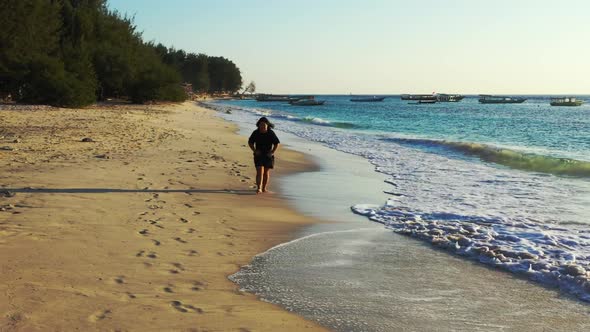 Tourist happy and smiling on idyllic coastline beach wildlife by blue green lagoon with white sandy 