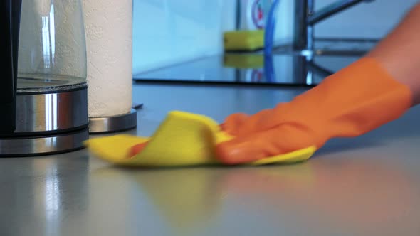 A Man with Rubber Gloves Cleans a Kitchen Counter with a Cloth - Closeup