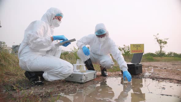 Two Ecologist full in PPE took took a sample of water for analysis.