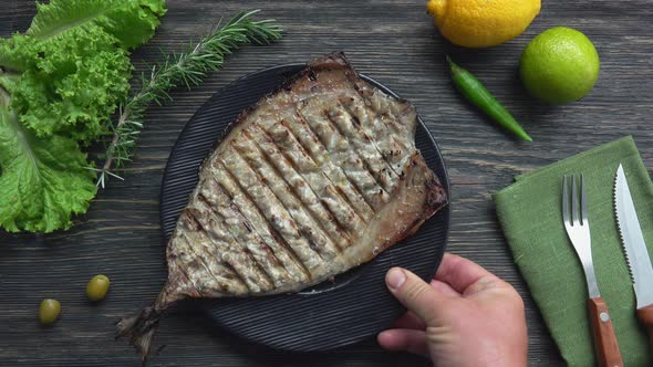 Top View of the Plate with a Juicy Grilled White Fish Placed on the Table