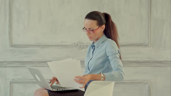 Attractive Businesswoman Reading Stats and Graphs on Paperwork