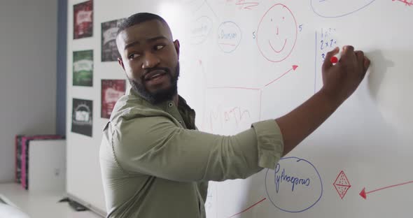 Video of happy african american male teacher at blackboard during math lesson