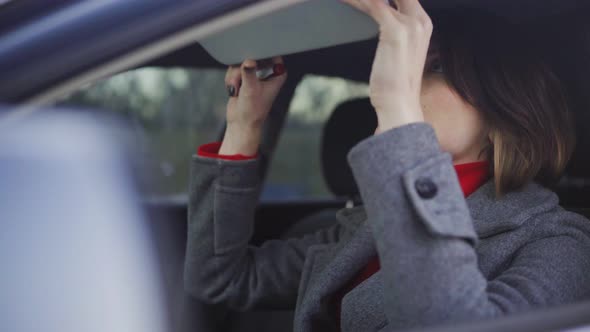 Business Woman in Grey Coat and Red Turtleneck Applying Makeup in the Car