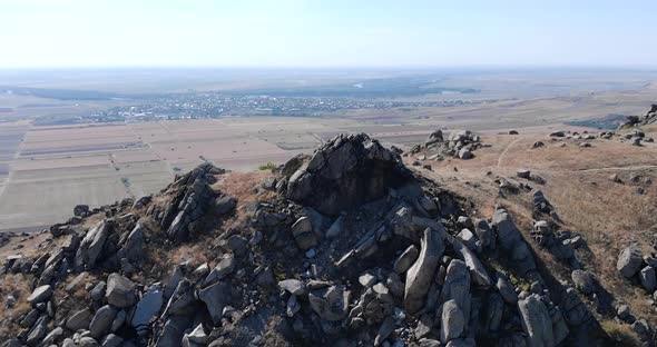 Aerial View Of Macin Mountain With Rocks And Crags Overlooking Countryside Field In Summer