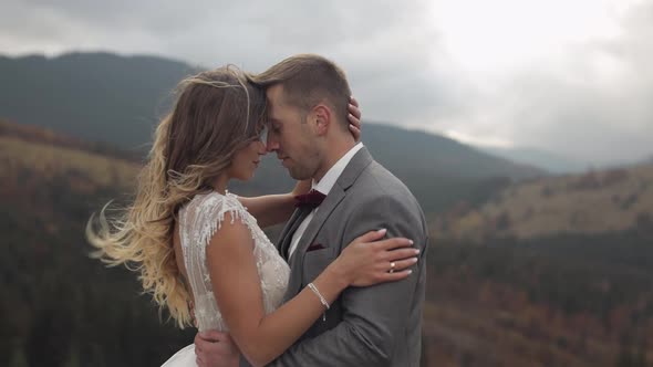 Lovely Young Newlyweds Bride and Groom Embracing Hugging on Mountain Slope Wedding Couple in Love