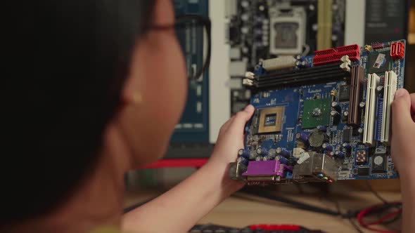 Asian Girl Is Working With Computer And Looking At Mainboard In Home, Display Showing Cad Software