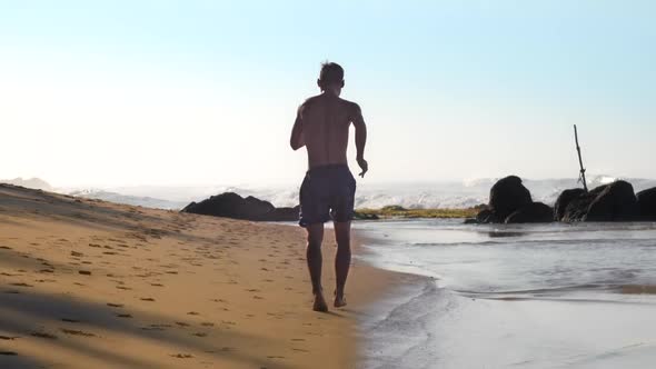 Athlete Runs Along Beach Against White Foaming Ocean Waves