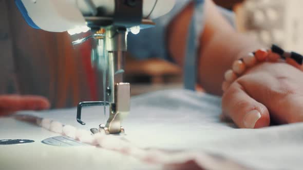 Hands of seamstress using sewing machine