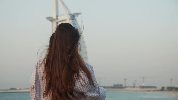 Woman Pointing at Burj Al Arab Hotel in Dubai During Sunset