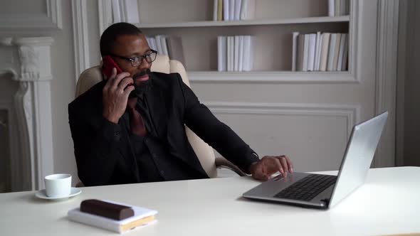 Confident Black Man Is Dressed Business Suit, Talking By Cell Phone in His Home Office
