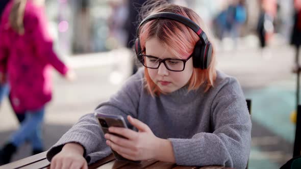 Children Internet and Video Games Addiction Little Girl is Watching Video By Smartphone in Cafe