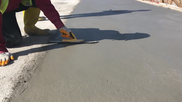 Construction Worker Uses Bullfloat to Flatten Cement Mortar Screed