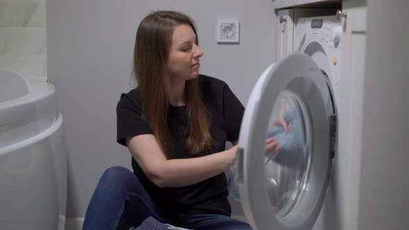 Woman Opens Door of Washing Machine Puts in Dirty Clothes and Takes Out Clothes