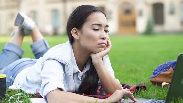 Unhappy and Tired Student Woman Lying on The Green Grass