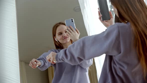 A Young Woman Dancer in Wireless Headphones Shoots Herself in the Mirror