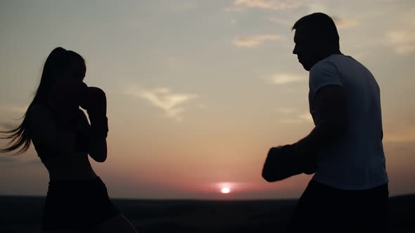 Female Boxer in Black Suit Trains with Trainer on Field