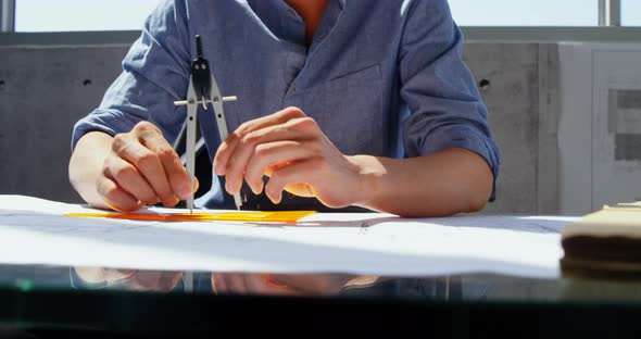 Front view of Asian male architect working on blueprint at desk in a modern office 4k