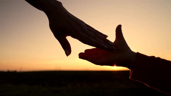 Mom and Child Holding Hands Together on Sunset Background