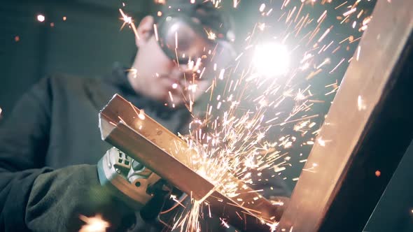 Male Worker Uses Angle Grinder at a Plant.