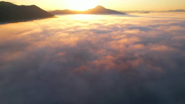 4K Scenic flight over beautiful mountain scape with bright sky and clouds on summer sunrise