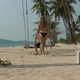 a Woman in a Swimsuit Approaches a Man Sitting on a Swing Suspended From a Palm Tree Sits Down and - VideoHive Item for Sale