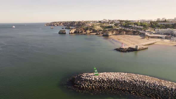 Aerial of the entrance to the Bensafrim River in Lagos, Portugal solitified by heavy wave breakers
