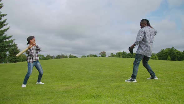 Active African American Dad and Cute Son Playing Baseball in Park