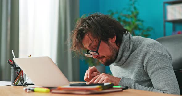 Focused Accountant with Serious Face Counts Company's Income on Calculator Taps Fingers on