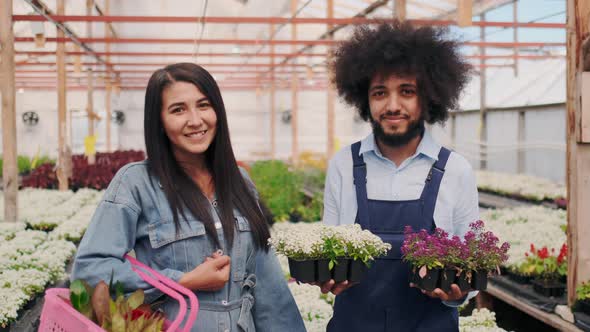 Friendly Arab Man with Curly Hair In Garden Uniform and Attractive Female Customer with Shopping Bag