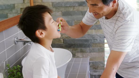 Father brushing his sons teeth in bathroom 4k