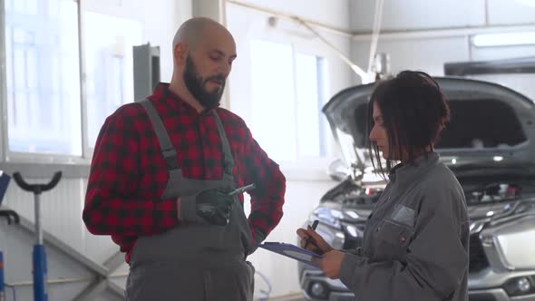 Two Professional Mechanics Female and Male in Car Repair Shop. Car Service, Repair and Maintenance