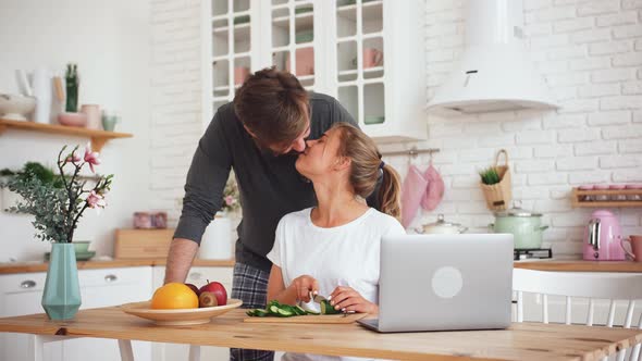 Young Loving Couple Preparing Vegatables for Salad in Kitchen During Beautiful Morning