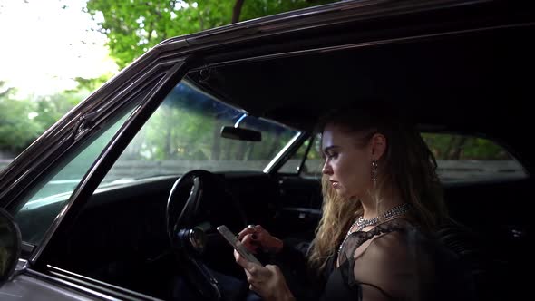 Sorrowful Woman Is Reading Messages in Smartphone and Suffering, Sitting Inside Expensive Car