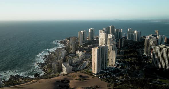 Aerial orbit of buildings next to dunes in concon chile at sunset