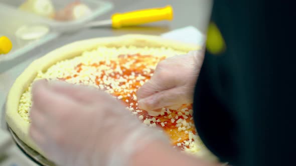 CU Cook Prepares Pizza Sprinkles It with Cheese