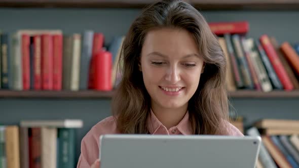 Young Student Using a Tablet Computer in a Library