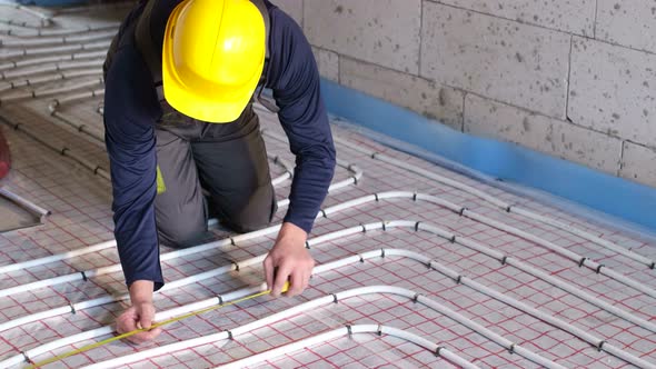 A Professional Craftsman Installs Pipes for Underfloor Heating