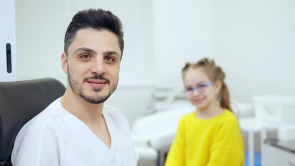 Portrait of Confident Male Middle Eastern Pediatrician Posing in Hospital with Blurred Caucasian