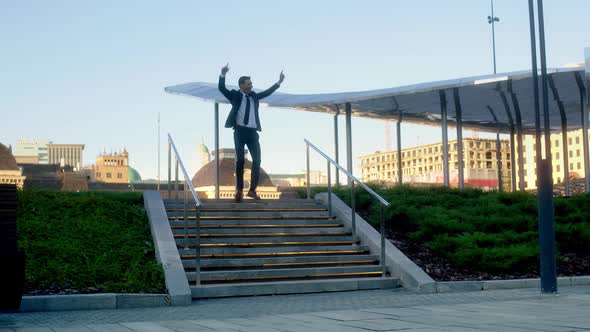 Successful Businessman in Suit Rejoices and Fools Around on Stairs Like Joker