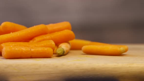 A pile of fresh, crisp, baby carrots on a wood cutting board.