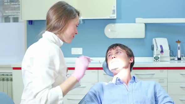 Female dentist doing routine check up to young male patient