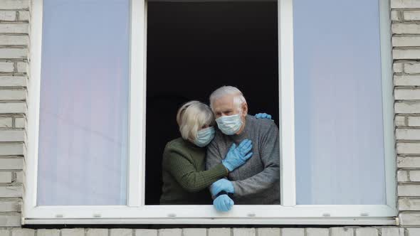 Old Grandparents Stay at Window Isolated at Home on Quarantine. Coronavirus