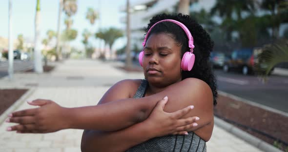 Curvy african woman doing sport stretching day routine outdoor 