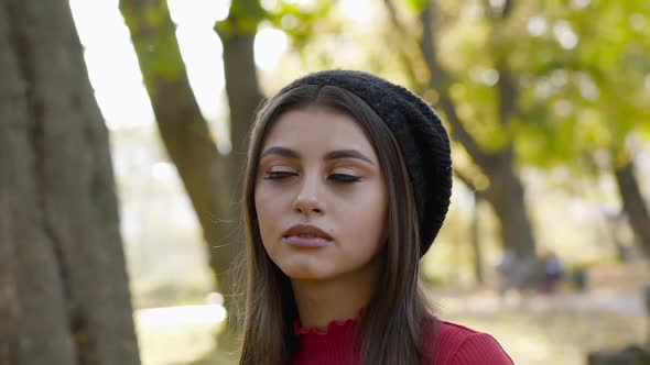 Young Lady in Beret Looking at the Sky and in Profile with Light Smile in Park