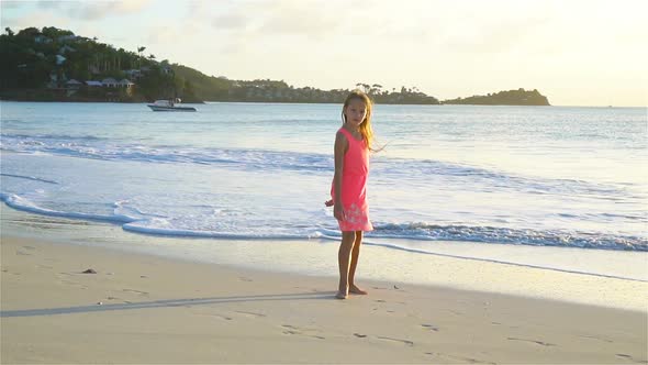 Adorable Happy Little Girl Having Fun on White Beach at Sunset