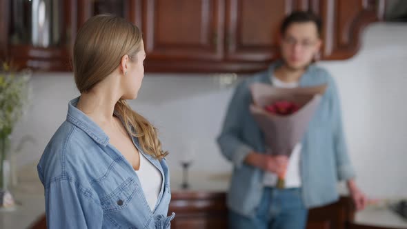 Young Offended Woman Looking Back at Blurred Man with Bouquet of Flowers Turning Crossing Hands
